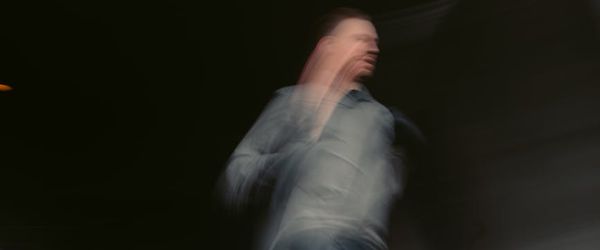 Blurred motion of an athlete running in a dark hall.