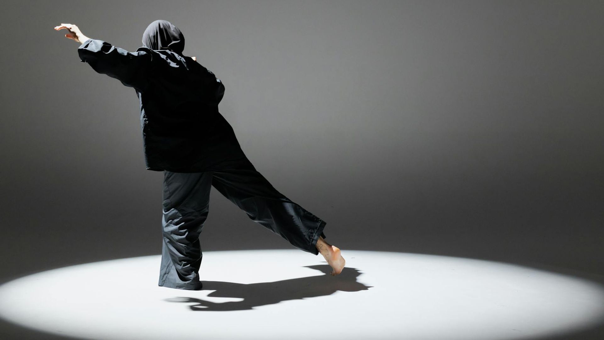 Person doing dynamic movements in a dark futuristic studio.